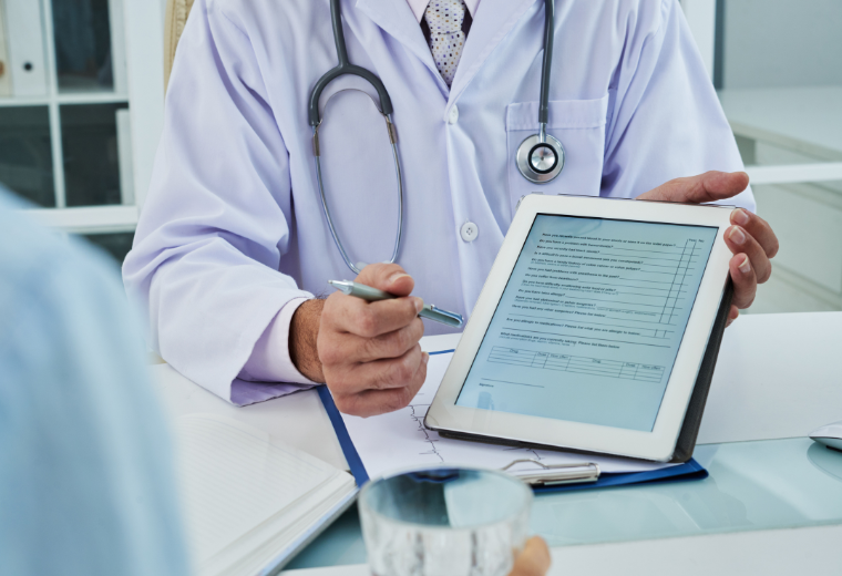 unrecognizable-doctor-extending-digital-tab-anonymous-patient-fill-questionnaire